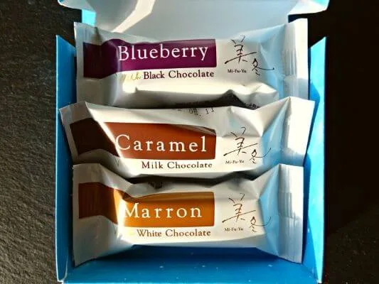 「石屋製菓」美冬のパッケージのふたを開けて中を見せている。中にはブルーベリー・キャラメル・マロンの3種類のミルフィーユが個包装で入っている。