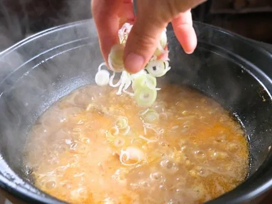 雑炊の上にネギを入れる