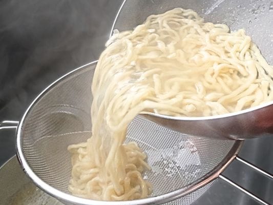 茹で上がった麺を湯切りする