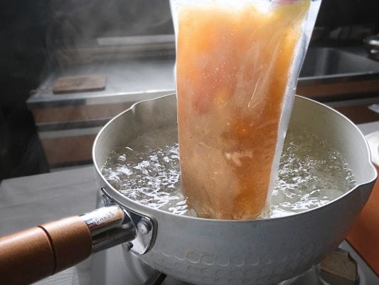 沸騰したお湯が入った雪平鍋の中に凍ったスープの袋をそのまま入れる。