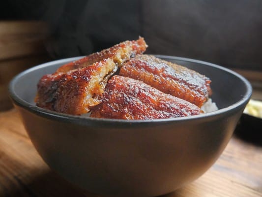 炭焼うな富士の国産青うなぎ長焼きをうな丼にして盛り付けた様子。湯気が立ち、たれがご飯にしみている
