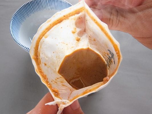 湯煎して温めた濃厚豚骨魚介スープの袋をオープン