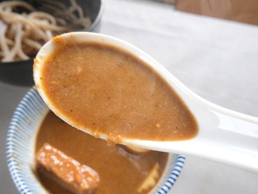 レンゲですくった超濃厚豚骨魚介スープをみると魚粉がういてるのがみえる