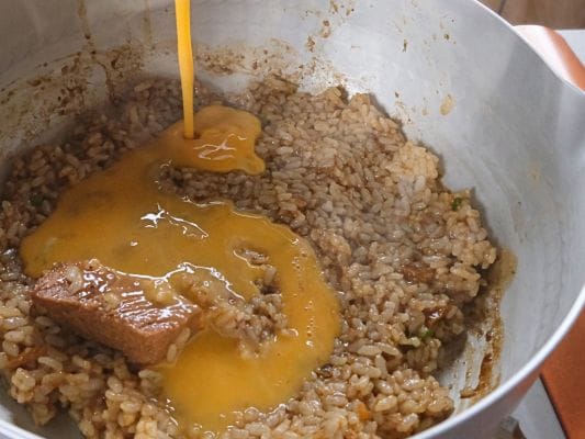 グツグツ煮立ったスープおじやに溶き卵を加えている調理シーン