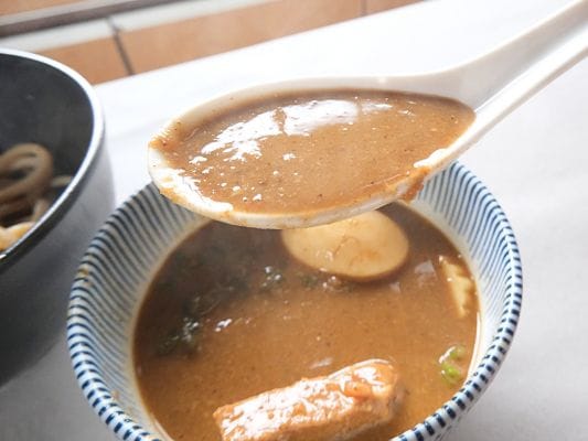 超濃厚豚骨魚介スープをレンゲですくっている