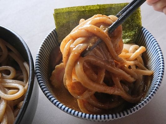 濃厚なつけ汁をしっかり絡めた極太麺を箸で持ち上げたところ