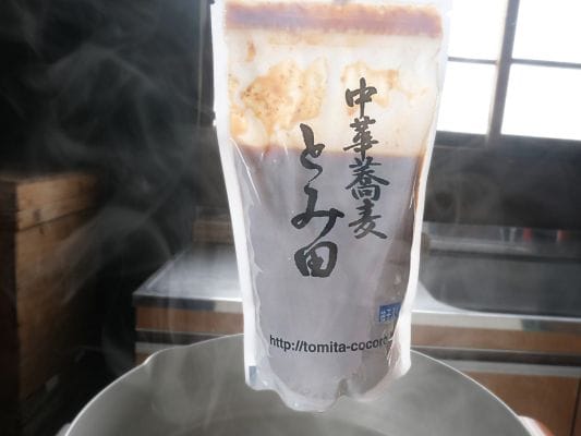 お湯から引き上げて湯気が出ているスープの袋