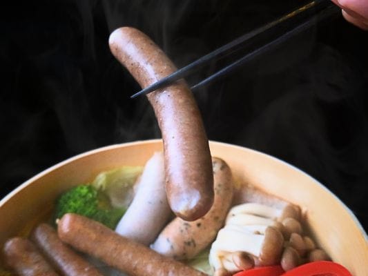 せいろ蒸しにしたあらびきを箸で持ち上げている。