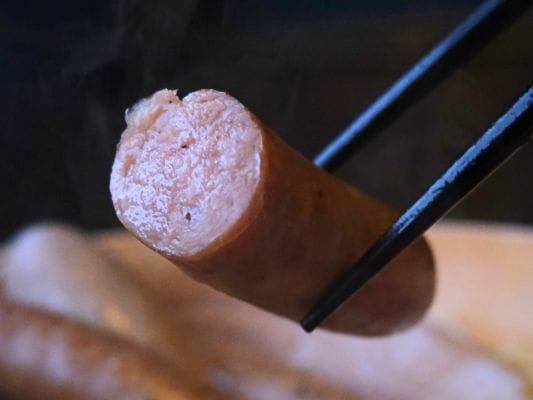 せいろ蒸しにして半分にカットしたあらびきを箸で持ち上げている。