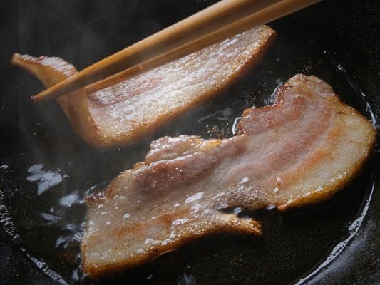 カットした厚さ約7mmのベーコンをフライパンで調理し終わった状態。焦げ目がついて脂が泡立っている。