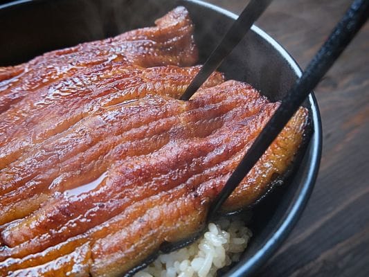 うなぎ処 古賀の蒲焼「竹」の鰻を箸でつまんで切ろうとしている