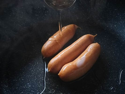 プリマハムの香薫あらびきポークをフライパンにのせてお水を大さじ3杯加えている。