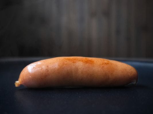 フライパンで焼いて少し焦げ目がついた丸大食品の燻製屋熟成あらびきポークウインナー。焼き立てで湯気が立っている。