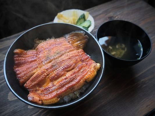 うなぎ処 古賀のお取り寄せ蒲焼「竹」をうな丼にして盛り付け。お吸い物とお漬物を添えている。