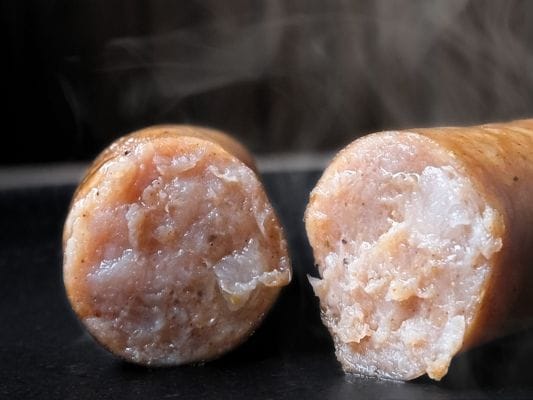 半分にカットしたあらびきの断面。脂がじんわり光り、黒胡椒の粒が入っているのがわかる。