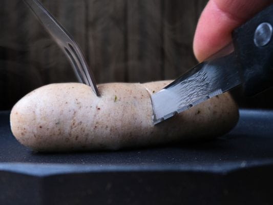 ヴァイスブルストをナイフでカットしている。太くて食べ応えのあるタイプ。
