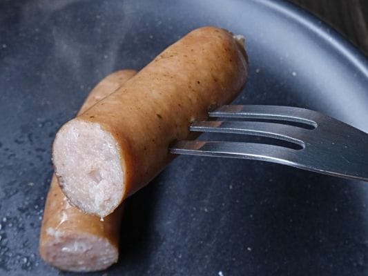 フォークで刺したスパイス。皮に張りがあり、断面には肉の色と脂が見える。