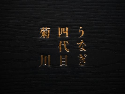 お取り寄せしたうなぎ四代目 菊川「一本うなぎ」の化粧箱に記載されているロゴ。金色の文字で「うなぎ四代目 菊川」