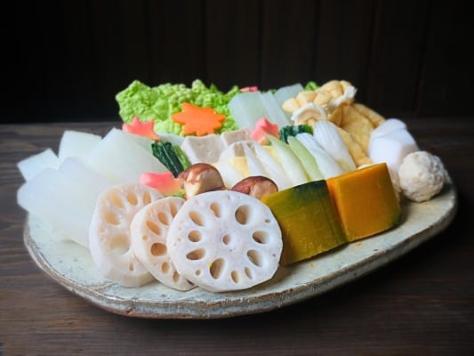 野菜や餅入り巾着、鶏団子、生麩などを更に盛り付けている