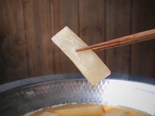 鍋で煮込んだ大根を箸で持ち上げている