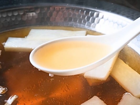 鍋で温めた特製だしをレンゲですくっている