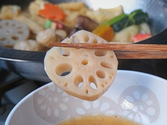 取り皿に取り分けたれんこんを箸で持ち上げている