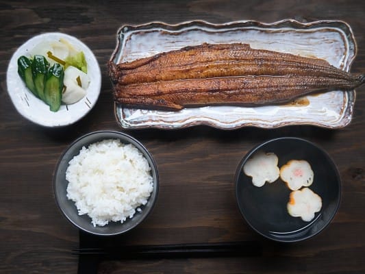 皿に盛り付けたうなぎ四代目 菊川「一本うなぎ」に白いご飯、お吸い物、漬物を添えている