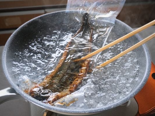 お取り寄せしたうなぎ四代目 菊川「一本うなぎ」を湯煎中、お湯の中で裏返しにしている