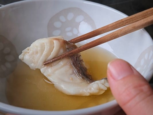 しゃぶしゃぶした真鯛を小皿に入った特製だしにつけている