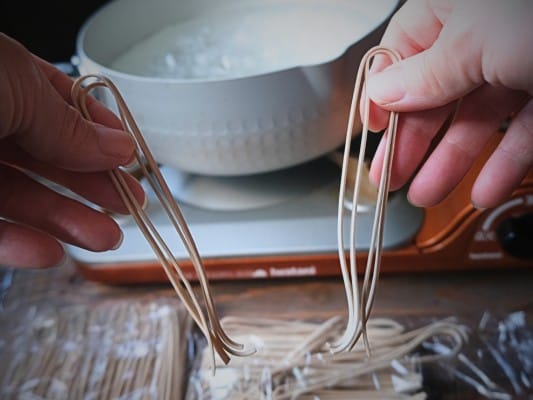 折りたたまれたれんこん麺の両端をもち、左右に広げて半分に折っている