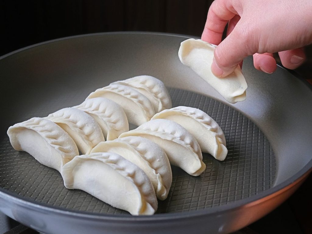 冷凍の魔法の焼き餃子を火をつける前のフライパンに並べる様子
