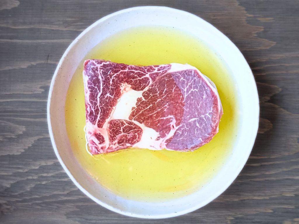 アルゼンチン産牛肉リブロースをオリーブオイルに浸して冷蔵庫で解凍する様子