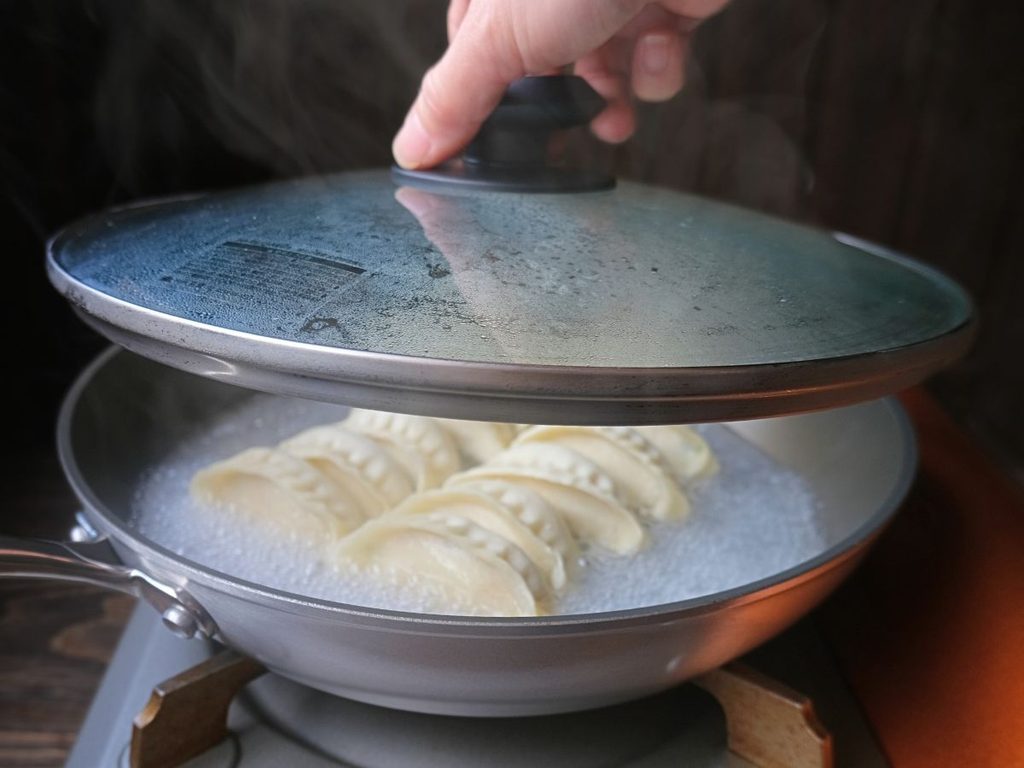 沸騰した魔法の焼き餃子にフタをして蒸し焼きにする様子