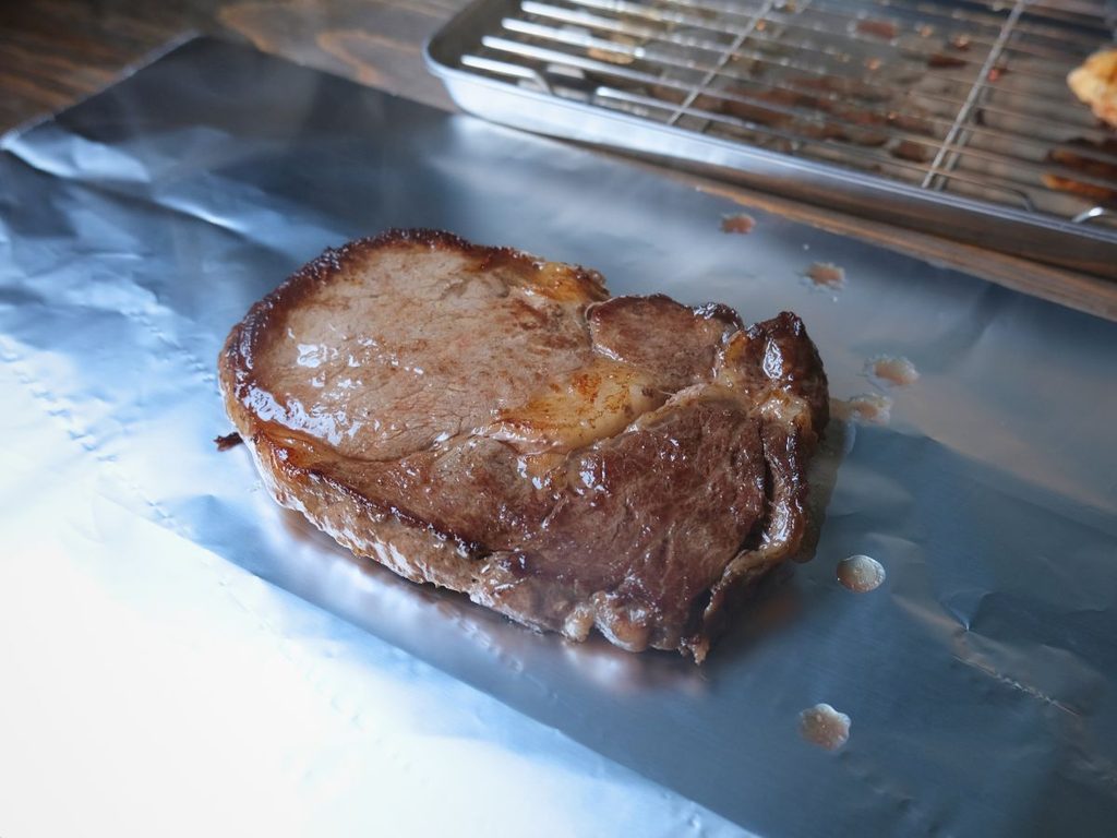 焼き上がったリブロースをアルミホイルで包む様子