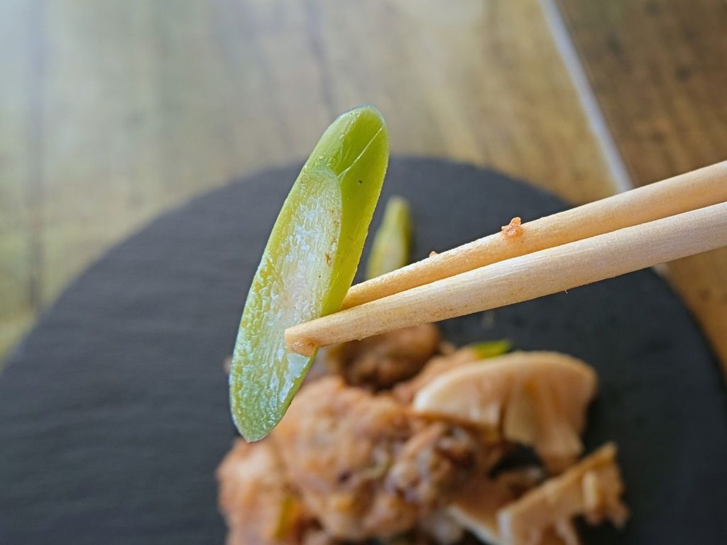 牡蠣の豆豉炒めに入っていたアスパラを箸で持ち上げた様子