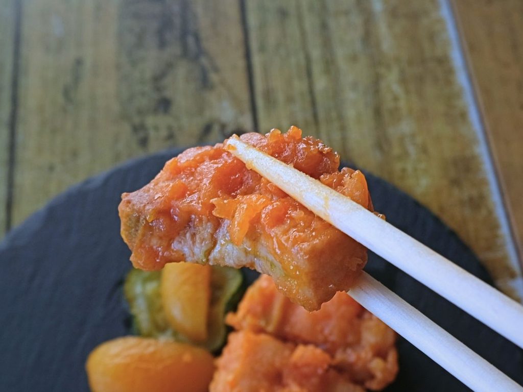 酢豚(杏子とズッキーニ添え)の豚肉を箸で持ち上げた断面