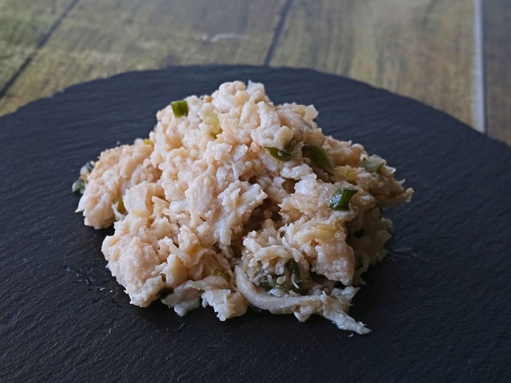 Oisix「本格中華オードブル 慶華2026」の蒸し鶏と香味野菜のソースを皿に盛り付けた様子