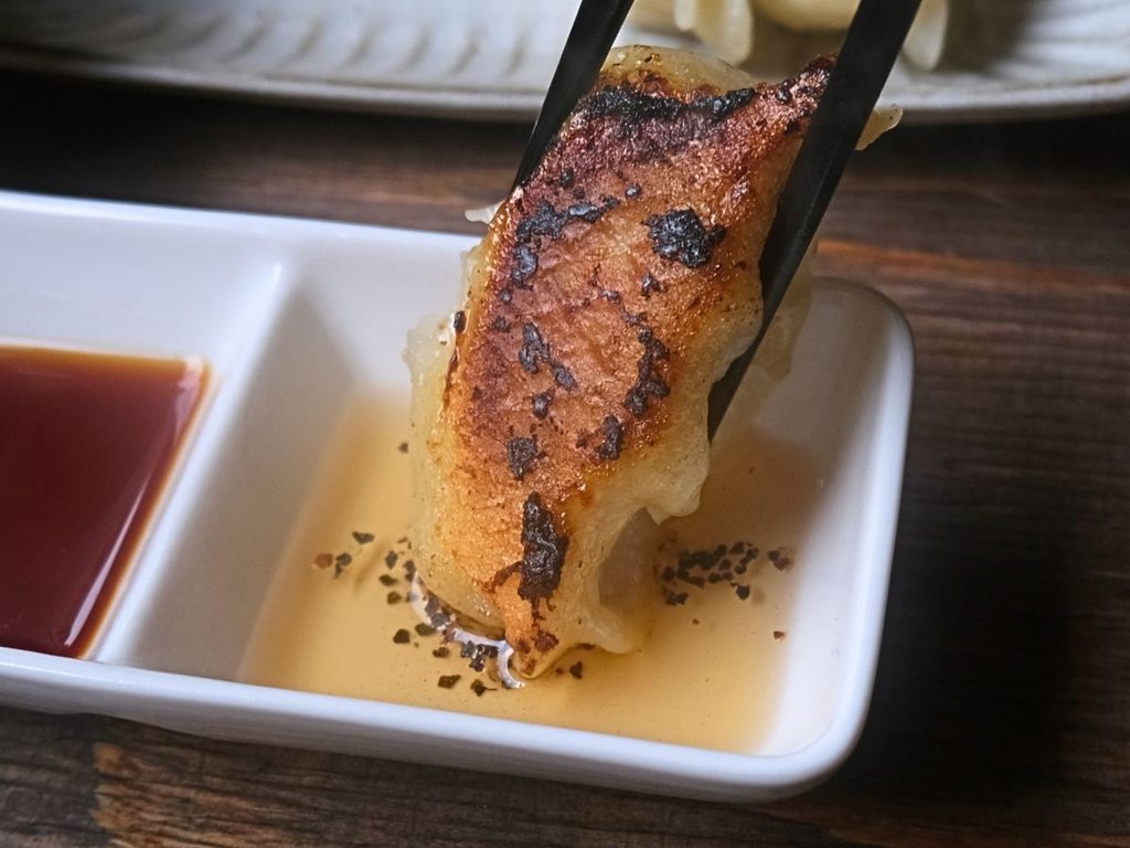 魔法の焼き餃子を酢胡椒につけて食べる様子