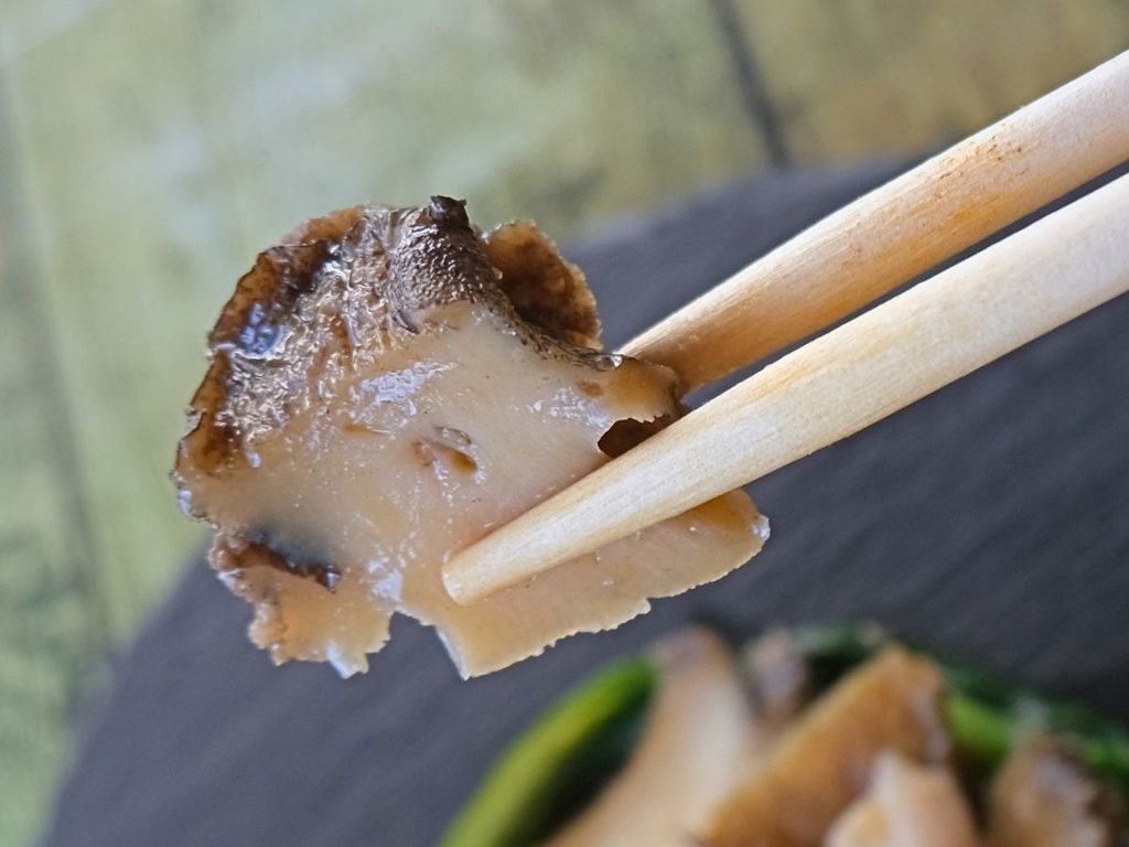 鮑の旨味スープ蒸しを箸で持ち上げた様子