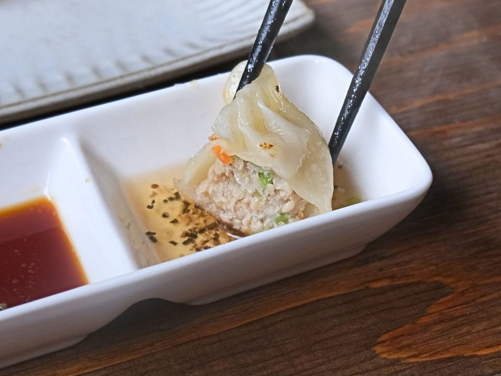 ひと口かじった魔法の焼き餃子を酢胡椒につけた様子