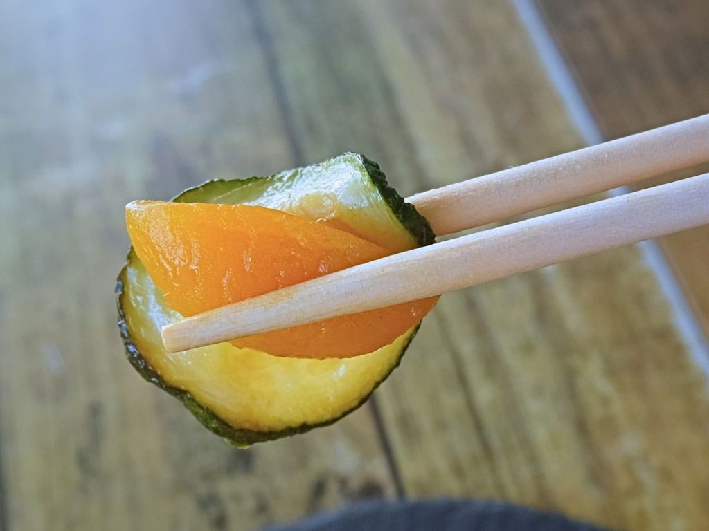 Oisix「本格中華オードブル 慶華2026」の酢豚に添えられた杏子とズッキーニを箸で持ち上げた様子
