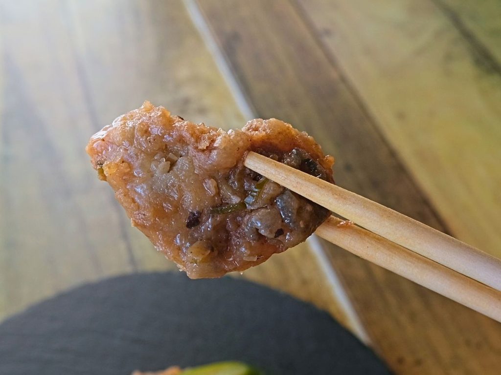 Oisix「本格中華オードブル 慶華2026」の牡蠣の豆豉炒めを箸で持ち上げた様子