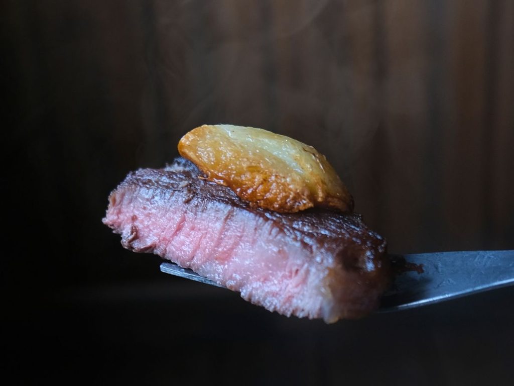焼き上がったアルゼンチン産牛肉リブロースと揚げ焼きにしたにんにく