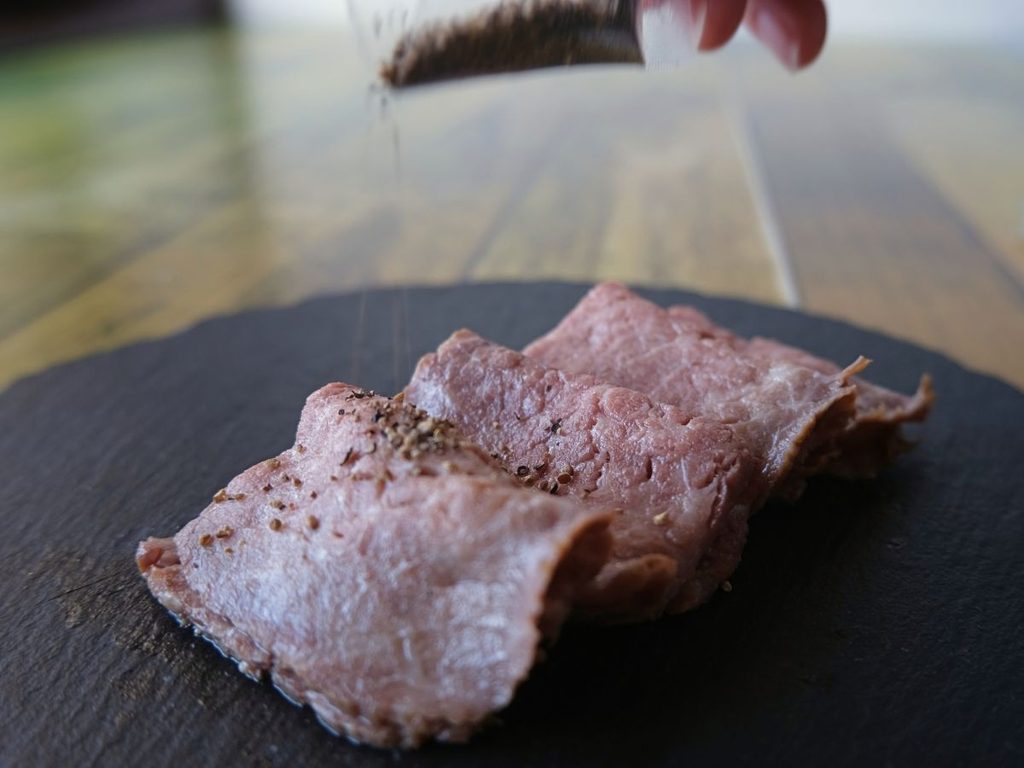 黒毛和牛のローストビーフに別添えの黒胡椒をかける様子